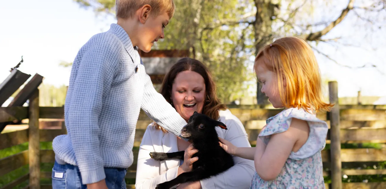 Mamma och barn gosar med svart lamm under evenemanget Åland Grönskar.