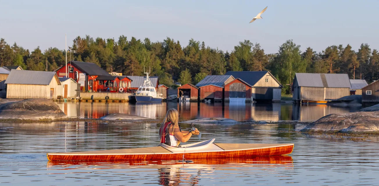 Kvinna som paddlar kajak vid fiskeläget i Käringsund.