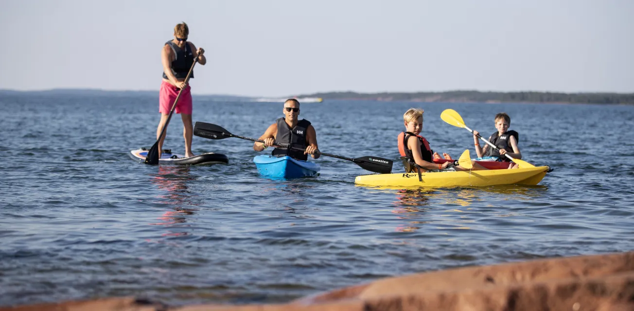 Barn och vuxna som paddlar kajak och SUP på Åland.