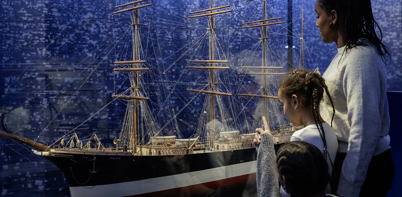 Familj tittar på fartygsmodellen av fartyget Ponape vid Ålands sjöfartsmuseum.