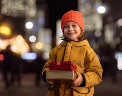 Leende barn i ytterkläder med två paket i händerna.