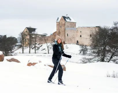 Kvinna skidar på golfbanan med Kastelholms slott i bakgrunden.