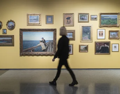 Kvinna tittar på tavlor i utställning vid Ålands konstmuseum.