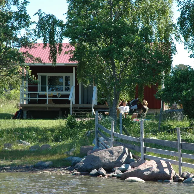 Röd stuga invid strand