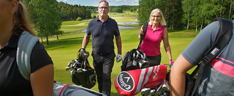 Golfspelare går mellan hålen på golfbanan i Kastelholm.