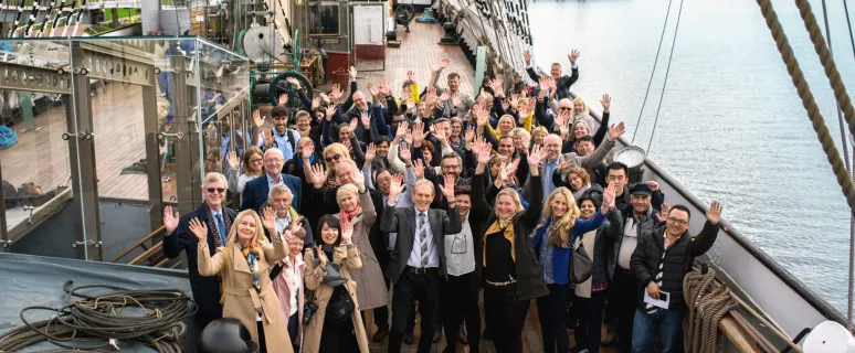 Konferensgrupp som vinkar mot kameran på fartyget Pommerns däck.