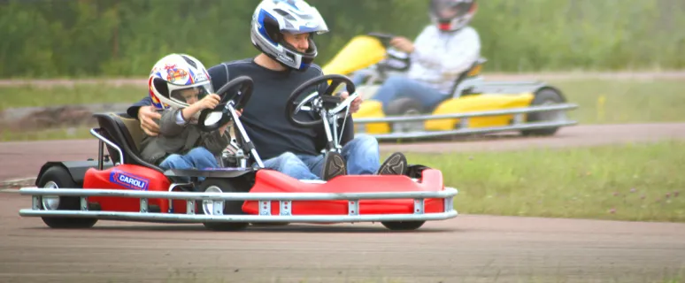 Barn och vuxen kör gokart tillsammans.
