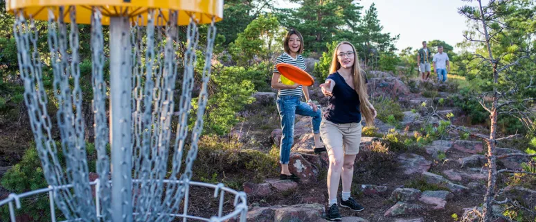 Två kvinnor kastar frisbeegolf vid Badhusparken i Mariehamn.