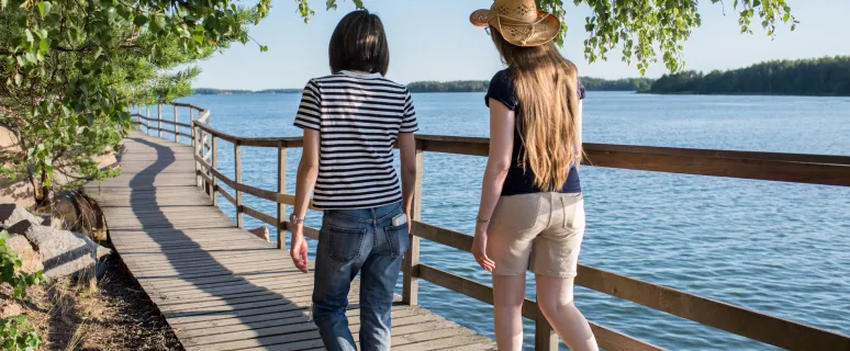 Två kvinnor promenerar längst strandpromenaden i Mariehamn.