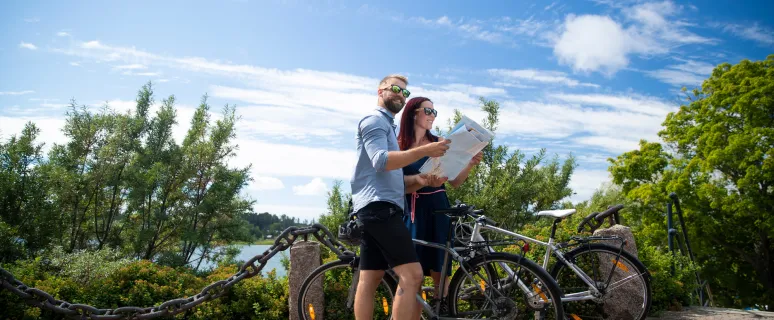 Par med cyklar som studerar cykelkarta på Åland.