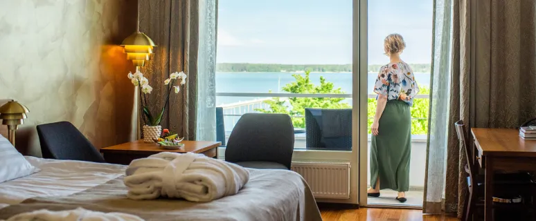 Hotellrum med kvinna stående på rummets balkong.