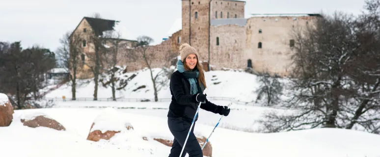Kvinna skidar på golfbanan med Kastelholms slott i bakgrunden.